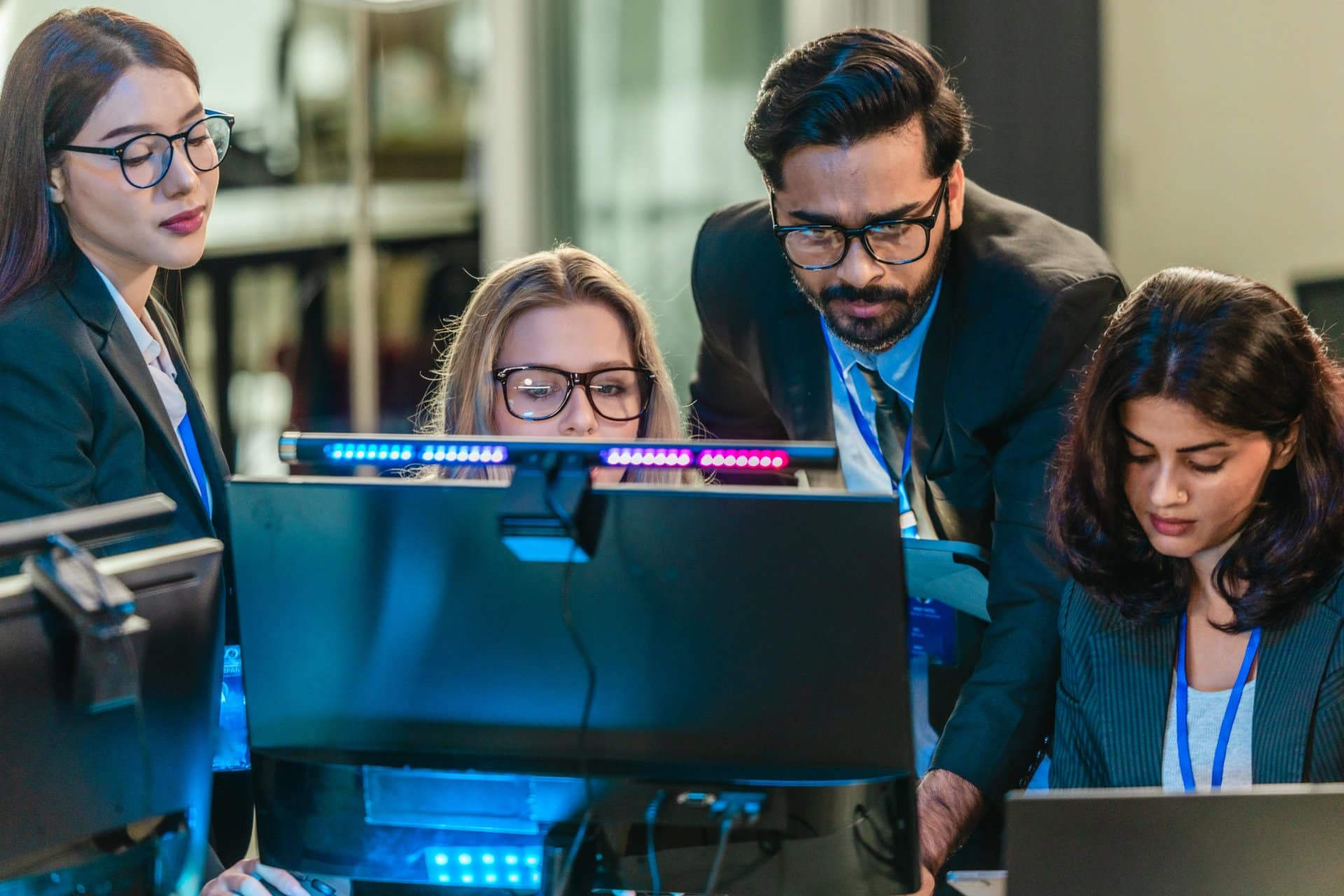 Professionals collaborate in  tech environment. Senior members coaching, mentoring, guiding colleagues through data analytics and software development. Knowledge sharing, leadership, technical growth