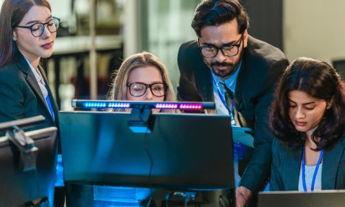 Professionals collaborate in  tech environment. Senior members coaching, mentoring, guiding colleagues through data analytics and software development. Knowledge sharing, leadership, technical growth